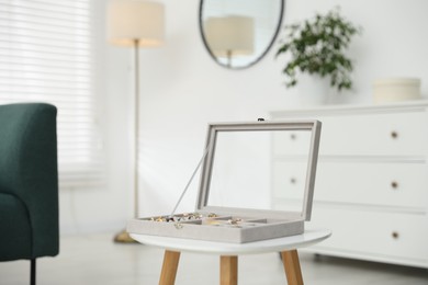 Photo of Jewelry box with many different accessories on white table indoors