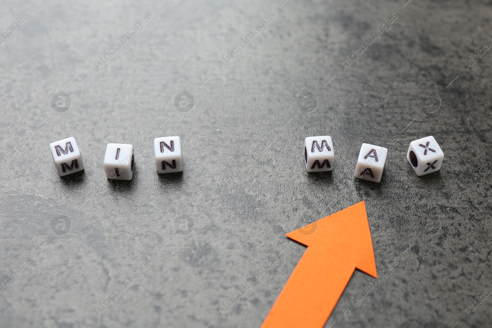 Words Min and Max made of cubes with arrow pointing at it on grey table, closeup Photo of Words Min and Max made of cubes with arrow pointing at it on grey table, closeup