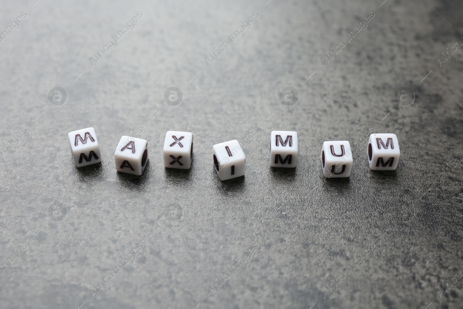 Word Maximum made of cubes on grey table, closeup Photo of Word Maximum made of cubes on grey table, closeup