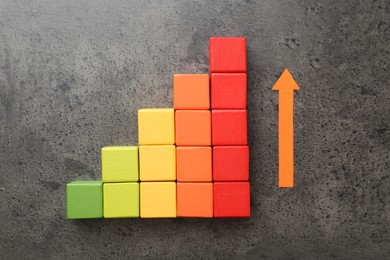 Photo of Maximum. Colorful cubes and arrow on grey table, flat lay