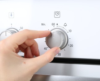Photo of Maximum concept. Woman turning on oven, closeup