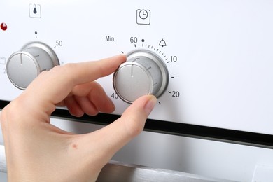 Photo of Maximum concept. Woman turning on oven, closeup