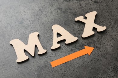 Photo of Word Max and arrow on grey table, closeup