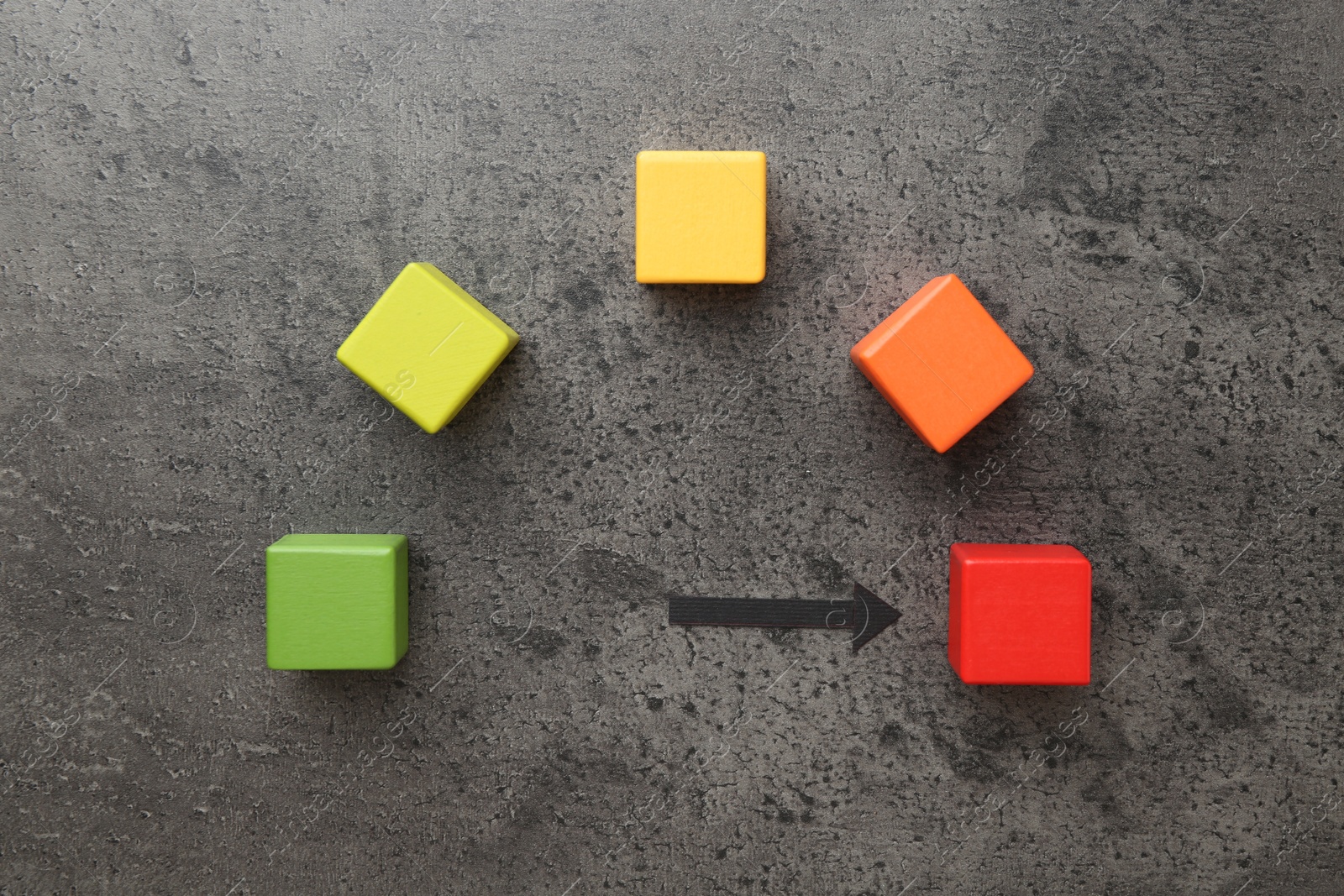 Maximum. Colorful cubes and arrow pointing at red one on grey table, flat lay Photo of Maximum. Colorful cubes and arrow pointing at red one on grey table, flat lay