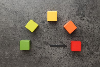 Photo of Maximum. Colorful cubes and arrow pointing at red one on grey table, flat lay