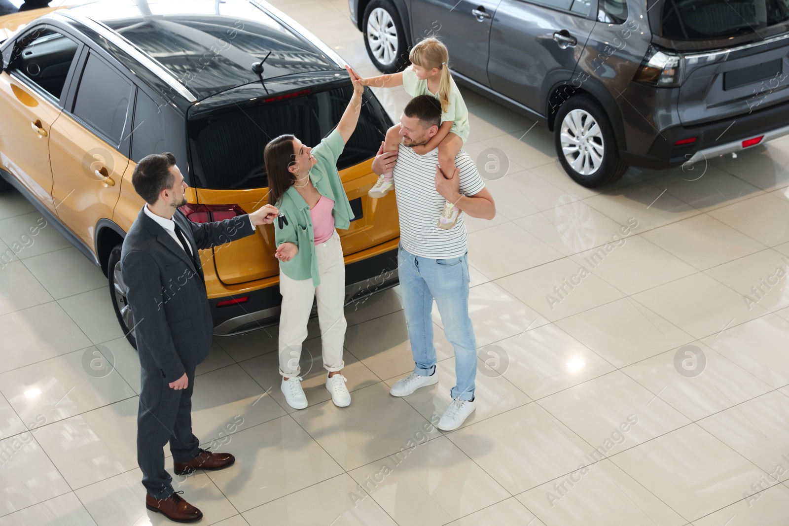 Salesman giving car key to happy family in salon Photo of Salesman giving car key to happy family in salon