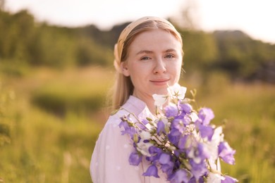 Photo of Beautiful woman with bouquet of wildflowers in meadow on sunny day. Space for text