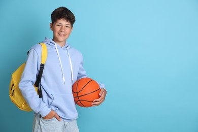 Photo of Teenage boy with backpack and basketball ball on light blue background, space for text
