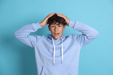 Photo of Portrait of shocked teenage boy on light blue background