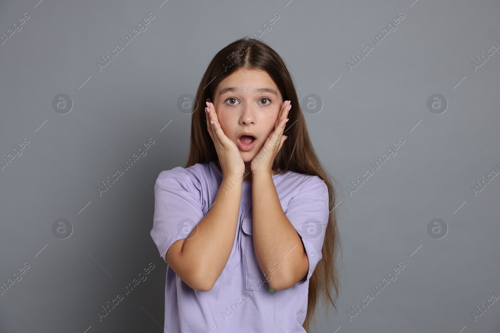Portrait of shocked teenage girl on grey background Photo of Portrait of shocked teenage girl on grey background