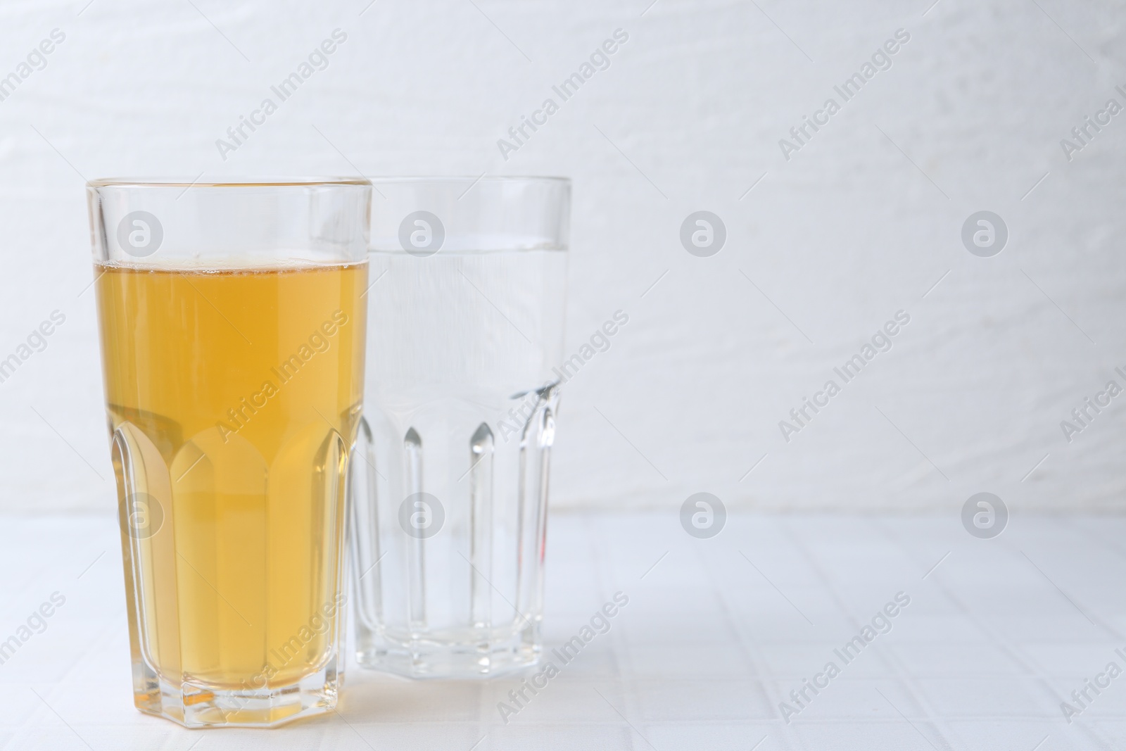 Glasses with clean and dirty water on white tiled table, closeup. Space for text Photo of Glasses with clean and dirty water on white tiled table, closeup. Space for text