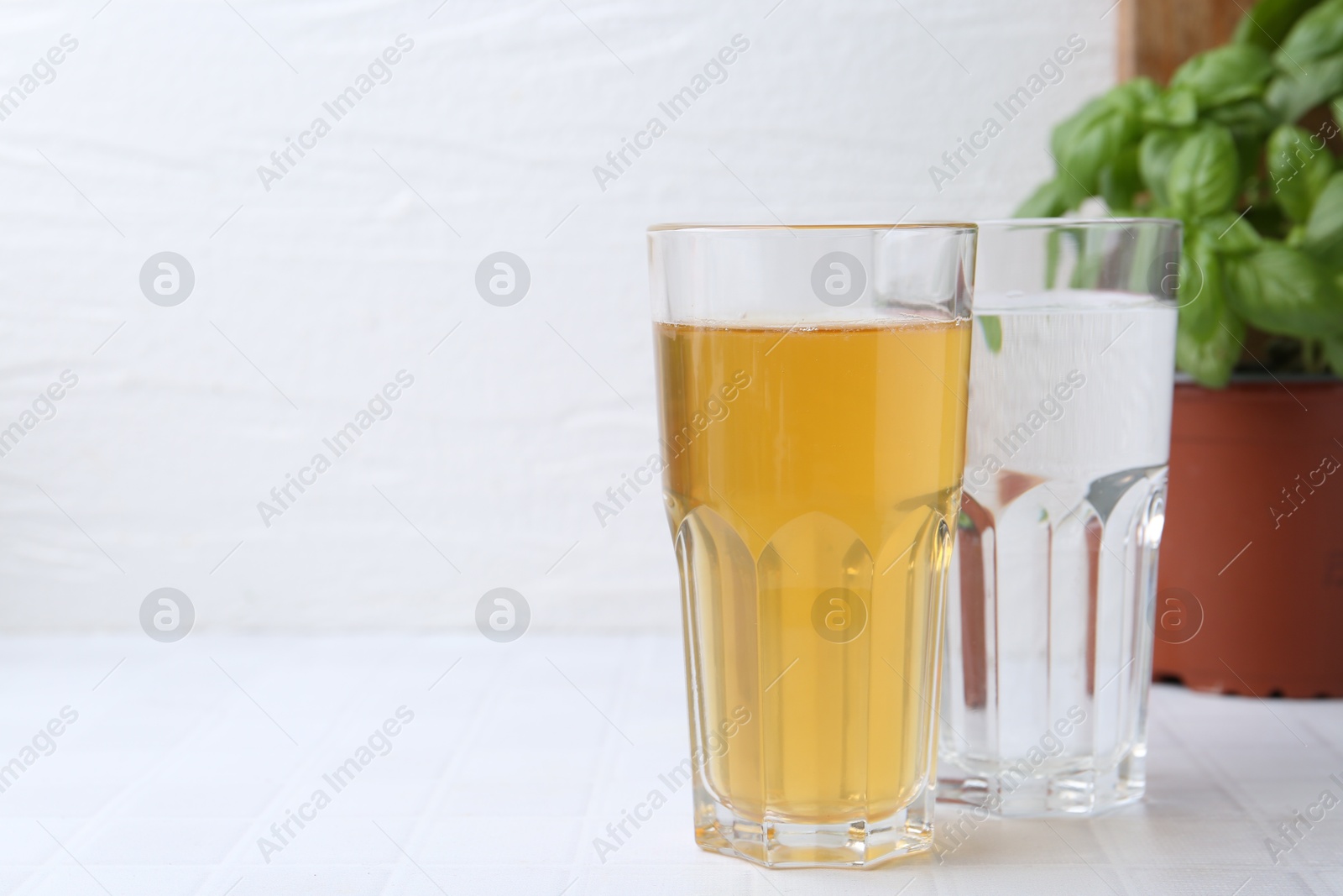 Photo of Glasses with clean and dirty water on white tiled table, closeup. Space for text