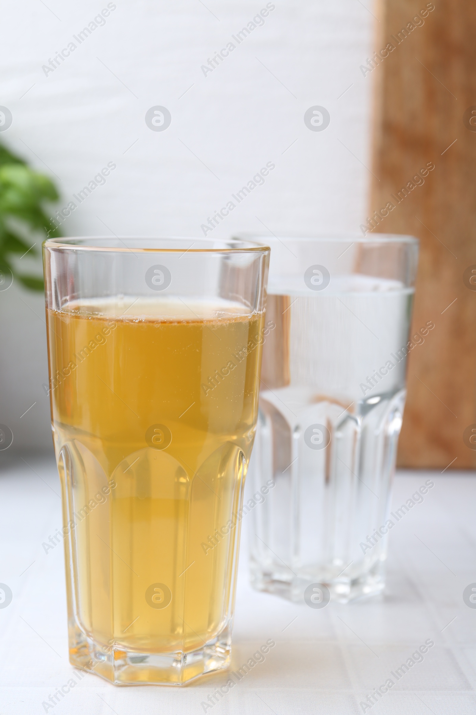 Photo of Glasses with clean and dirty water on white tiled table, closeup