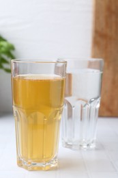 Photo of Glasses with clean and dirty water on white tiled table, closeup