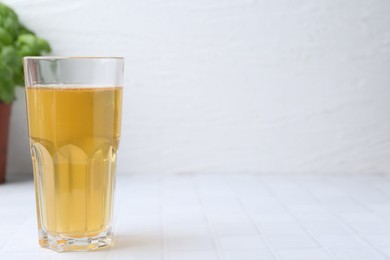 Photo of Glass with dirty water on white tiled table, closeup. Space for text