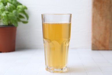 Photo of Glass with dirty water on white tiled table, closeup