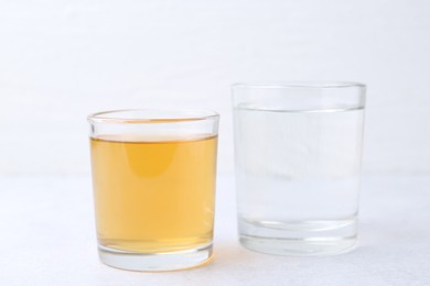 Photo of Glasses with clean and dirty water on light table, closeup
