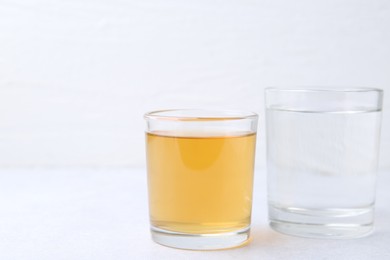 Photo of Glasses with clean and dirty water on light table, closeup. Space for text