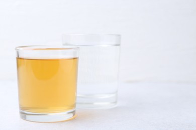 Photo of Glasses with clean and dirty water on light table, closeup. Space for text