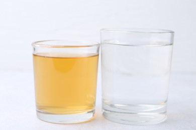 Photo of Glasses with clean and dirty water on light table, closeup