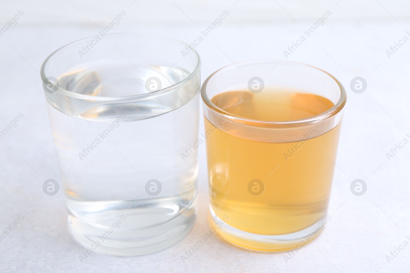 Photo of Glasses with clean and dirty water on light table, closeup