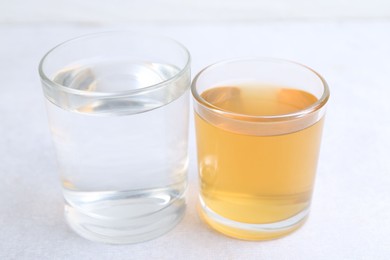 Photo of Glasses with clean and dirty water on light table, closeup
