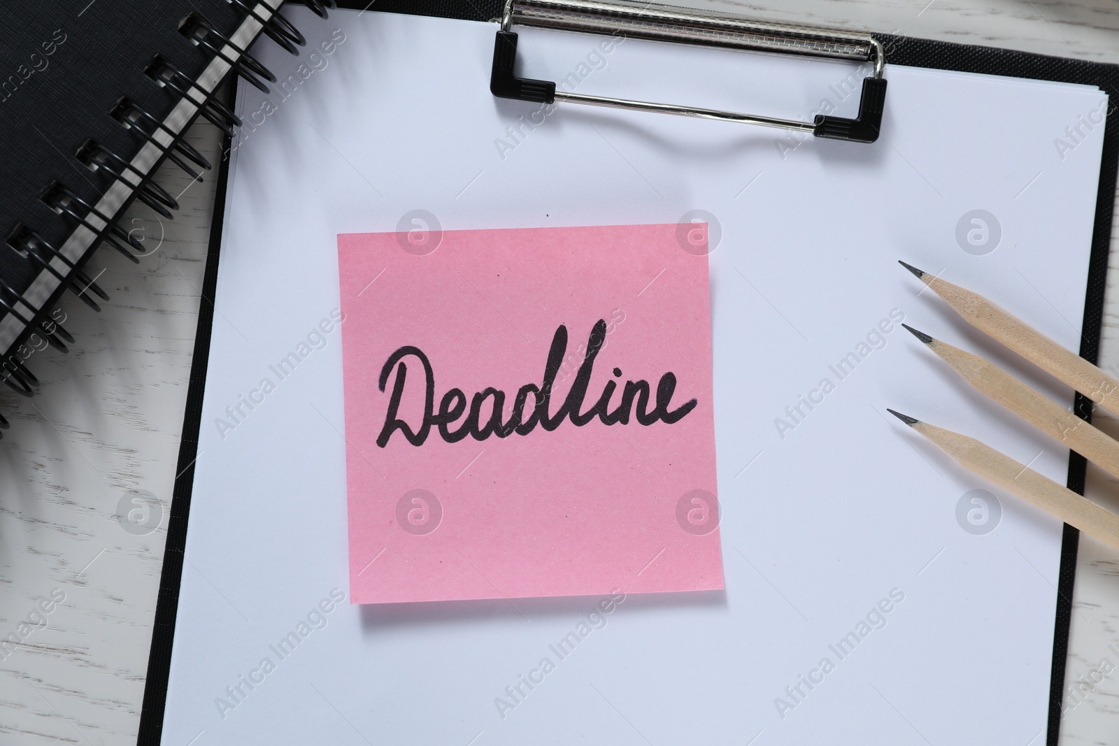 Sticky note with word Deadline, clipboard, notebook and pencils on white wooden table, top view Photo of Sticky note with word Deadline, clipboard, notebook and pencils on white wooden table, top view