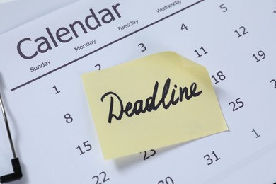 Photo of Sticky note with word Deadline and calendar on table, closeup