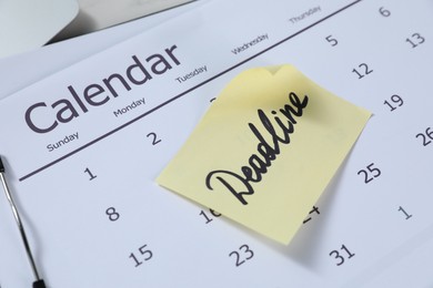 Photo of Sticky note with word Deadline and calendar on table, closeup