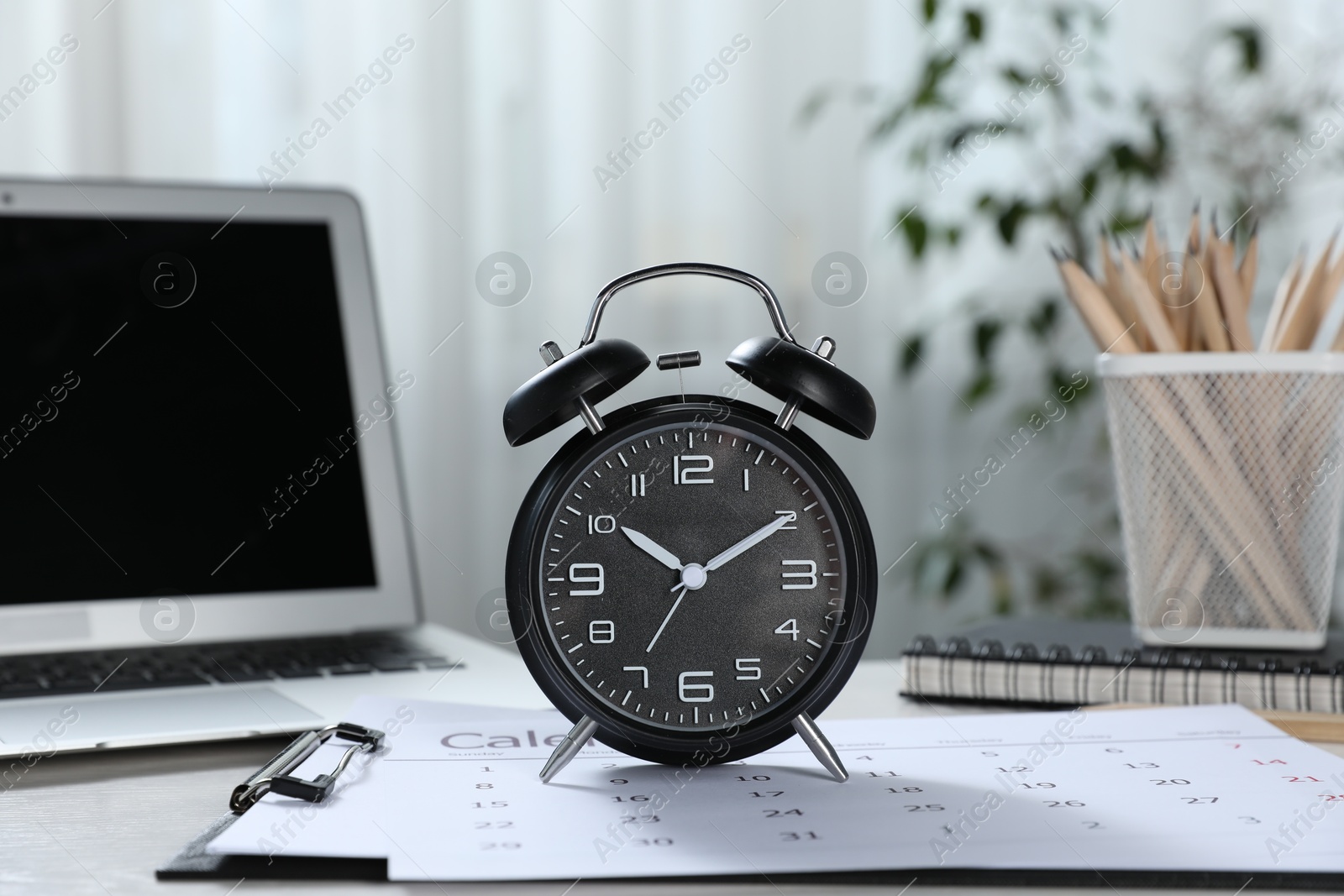 Deadline. Alarm clock, laptop, stationery and calendar on table indoors Photo of Deadline. Alarm clock, laptop, stationery and calendar on table indoors