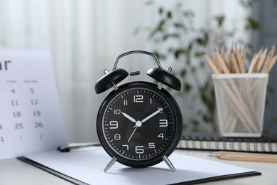 Photo of Deadline. Alarm clock, stationery and calendar on table indoors