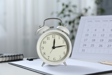 Photo of Deadline. Alarm clock, stationery and calendar on table indoors
