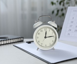Photo of Deadline. Alarm clock, stationery and calendar on light table indoors