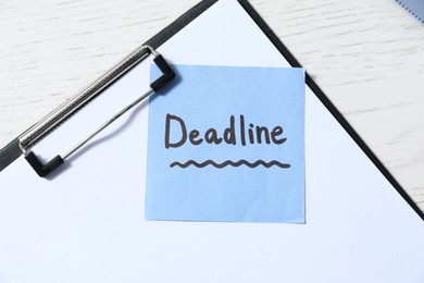 Photo of Sticky note with word Deadline and clipboard on white wooden table, top view