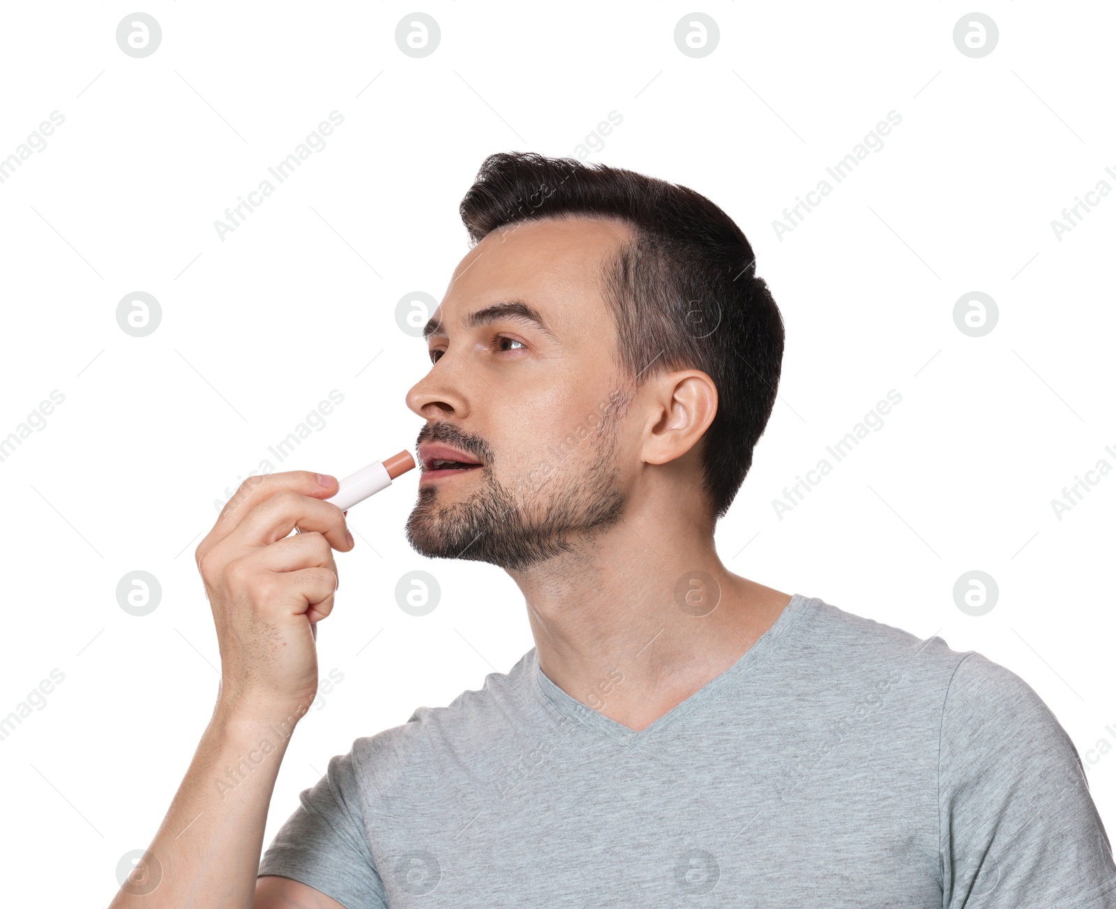 Photo of Handsome man applying lip balm onto his lips on white background