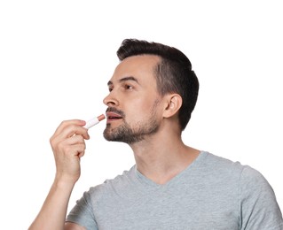 Photo of Handsome man applying lip balm onto his lips on white background