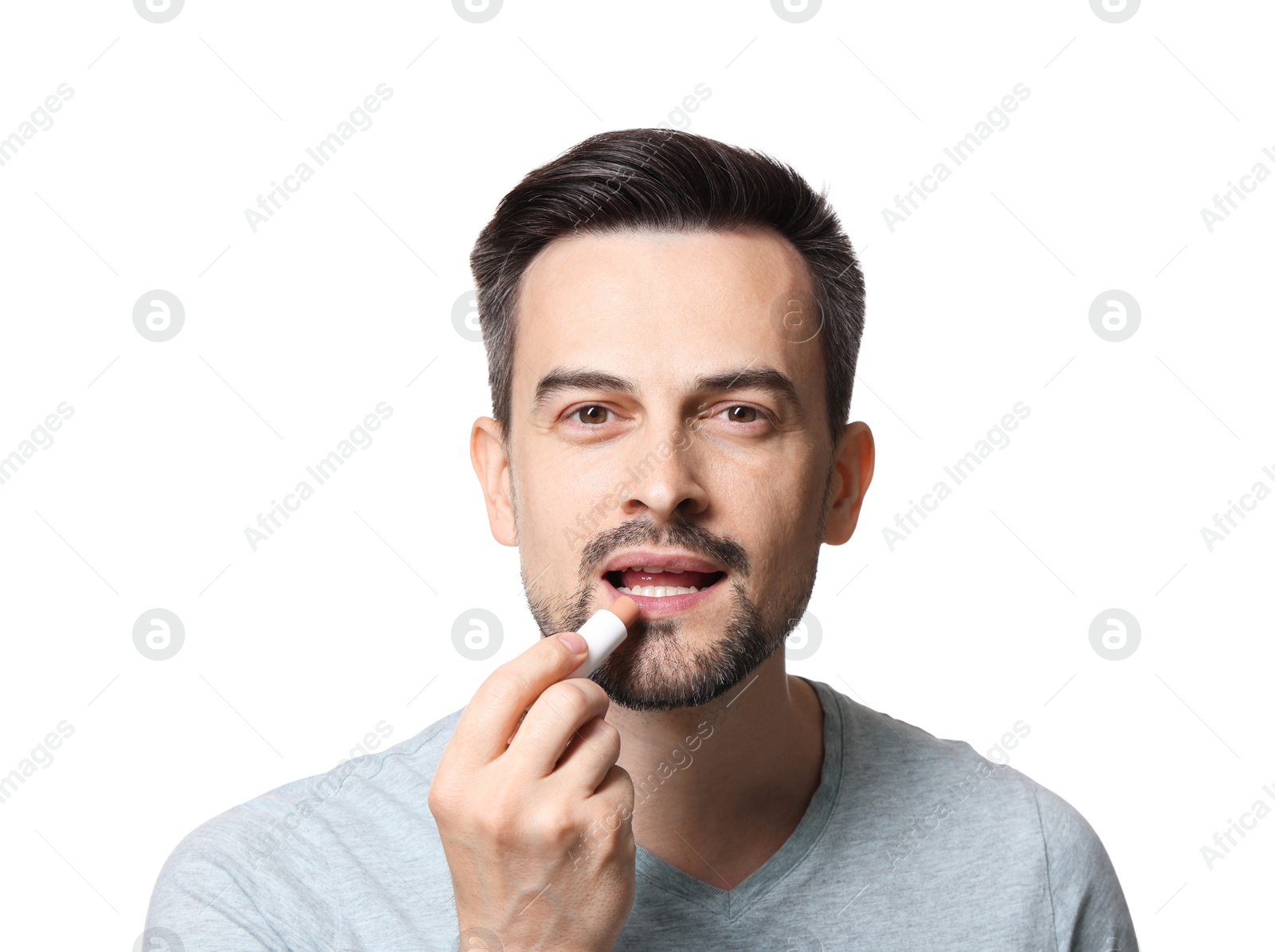 Handsome man applying lip balm onto his lips on white background Photo of Handsome man applying lip balm onto his lips on white background
