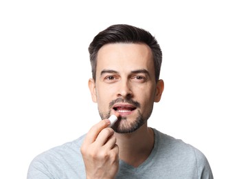 Photo of Handsome man applying lip balm onto his lips on white background