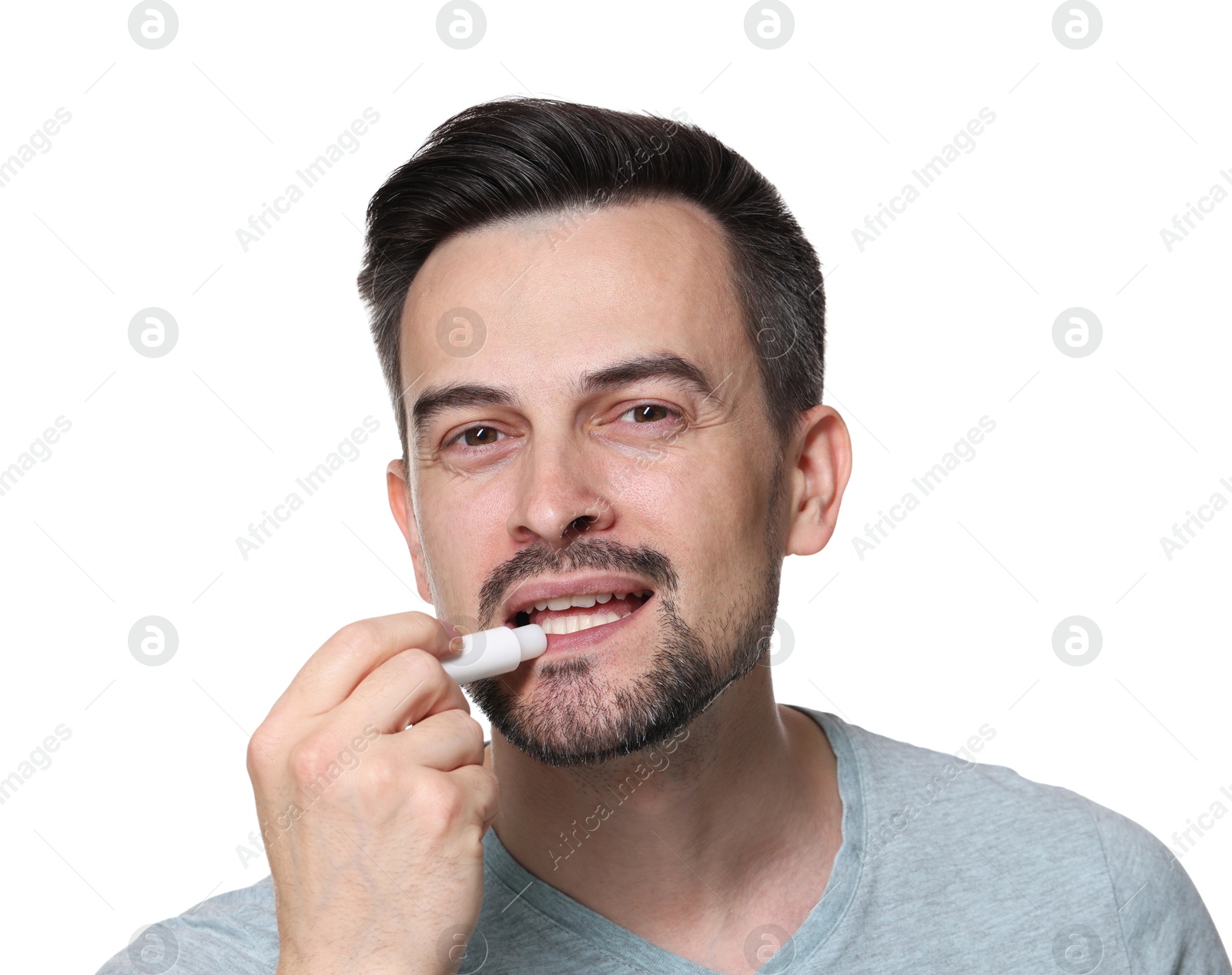 Handsome man applying lip balm onto his lips on white background Photo of Handsome man applying lip balm onto his lips on white background