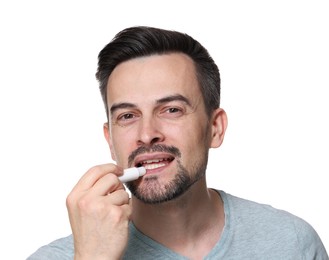 Photo of Handsome man applying lip balm onto his lips on white background