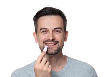 Photo of Smiling man applying lip balm onto his lips on white background