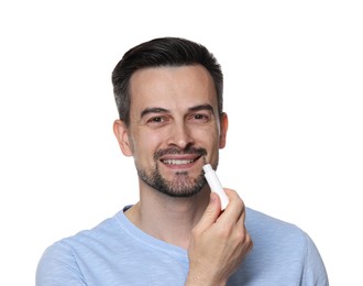 Photo of Smiling man applying lip balm onto his lips on white background