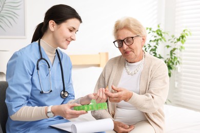 Photo of Nurse giving pills to senior woman indoors. Home health care service