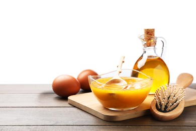 Photo of Homemade hair mask in bowl, fresh ingredients and brush on wooden table against white background. Space for text