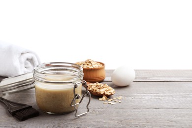 Photo of Homemade hair mask in jar, fresh ingredients and brush on grey wooden table against white background. Space for text