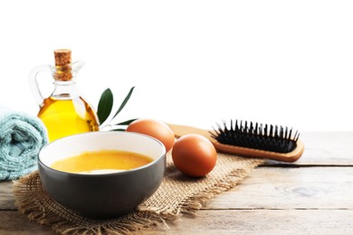 Photo of Homemade hair mask in bowl, fresh ingredients and brush on wooden table against white background. Space for text
