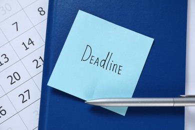 Photo of Sticky note with word Deadline, notebook, pen and calendar on table, top view
