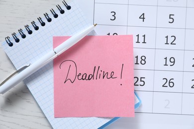 Photo of Sticky note with word Deadline, notebook, calendar and pen on white wooden table, top view