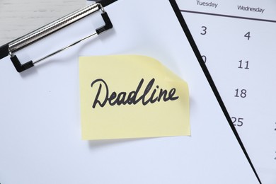 Photo of Sticky note with word Deadline, clipboard and calendar on table, top view