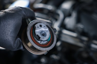 Photo of Auto part. Professional mechanic with idler-wheel near open hood of car indoors, closeup. Space for text